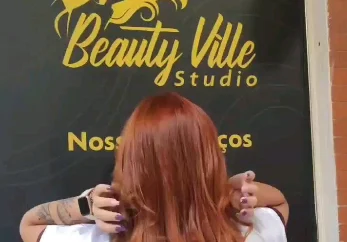 Cabelo ruivo intenso e ondulado em frente ao painel do salão